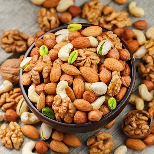 Wooden bowl with mixed nuts on a wooden gray background. Healthy food and snacks, organic vegetarian meals. Walnut, pistachios, almonds, hazelnuts and cashews, walnut.
